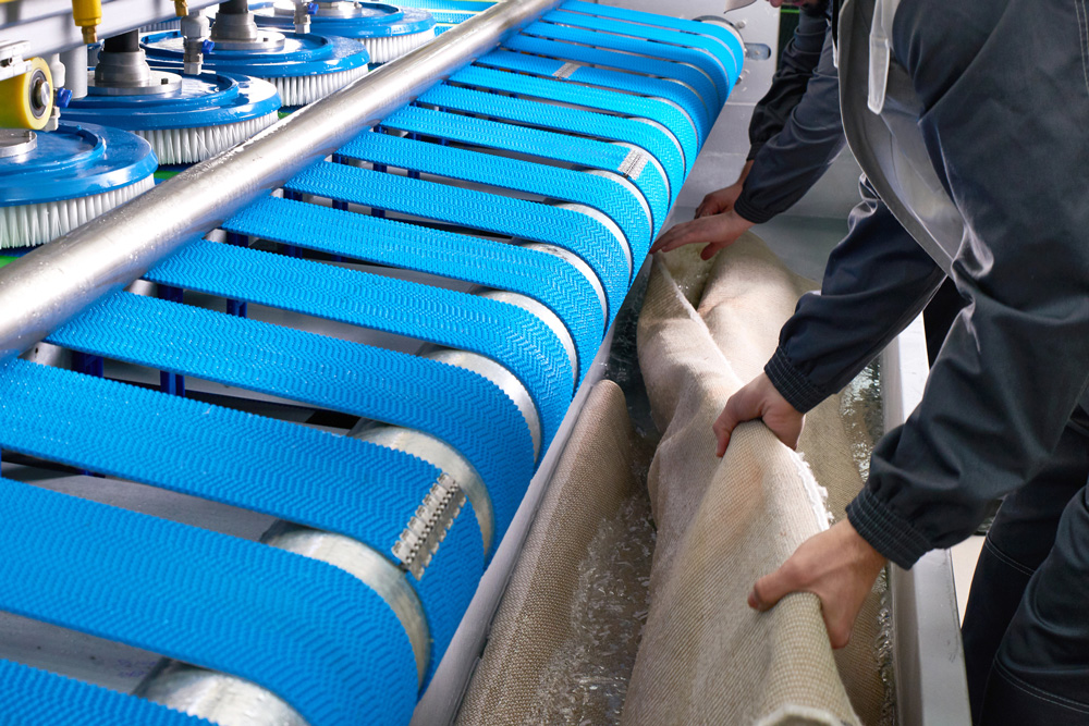 laundry worker in the process of working on an automatic machine for carpet washing